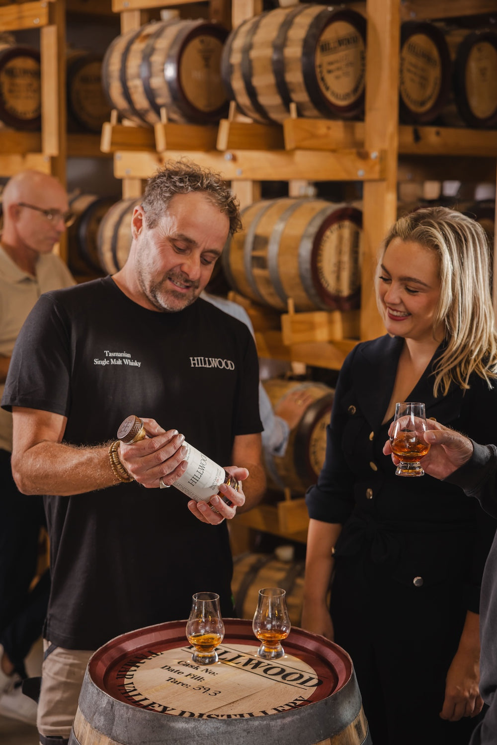 Ollie showing a Hillwood Whisky distillery visitor the whisky bottle and telling them all about their family Hillwood Whisky