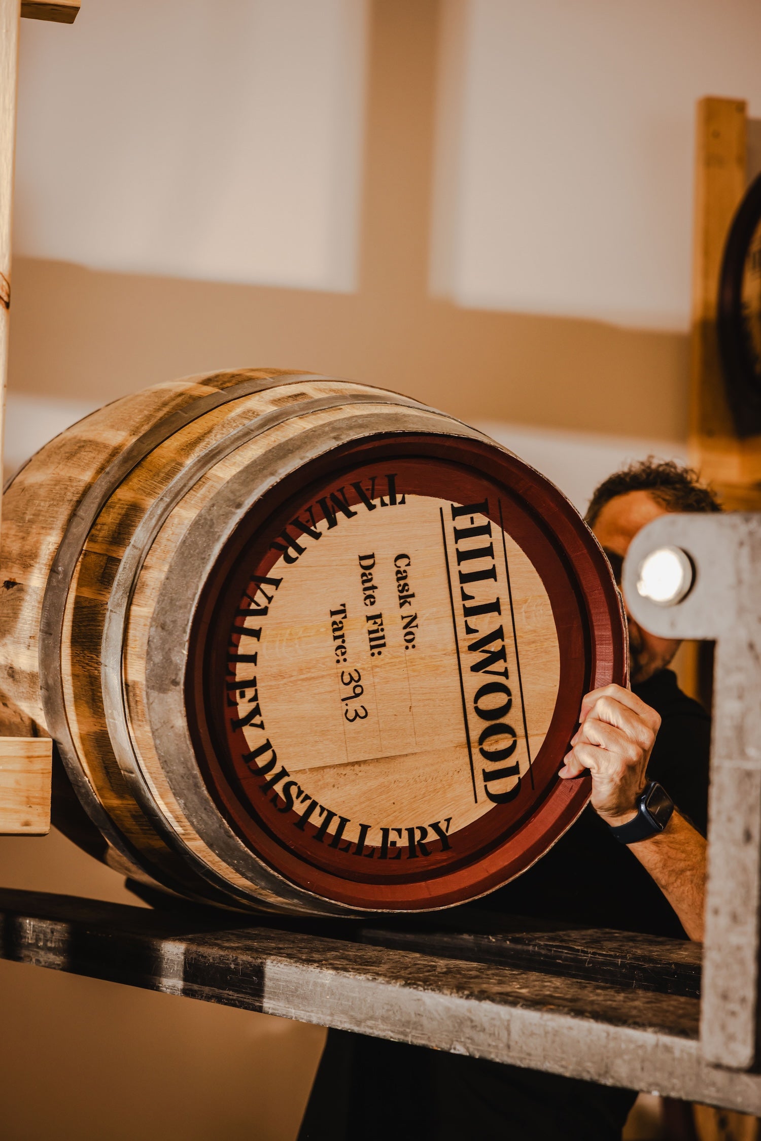 Hillwood Ollie lifting a Hillwood Whisky Cask with the words Tamar Valley Distillery on the face of the cask.